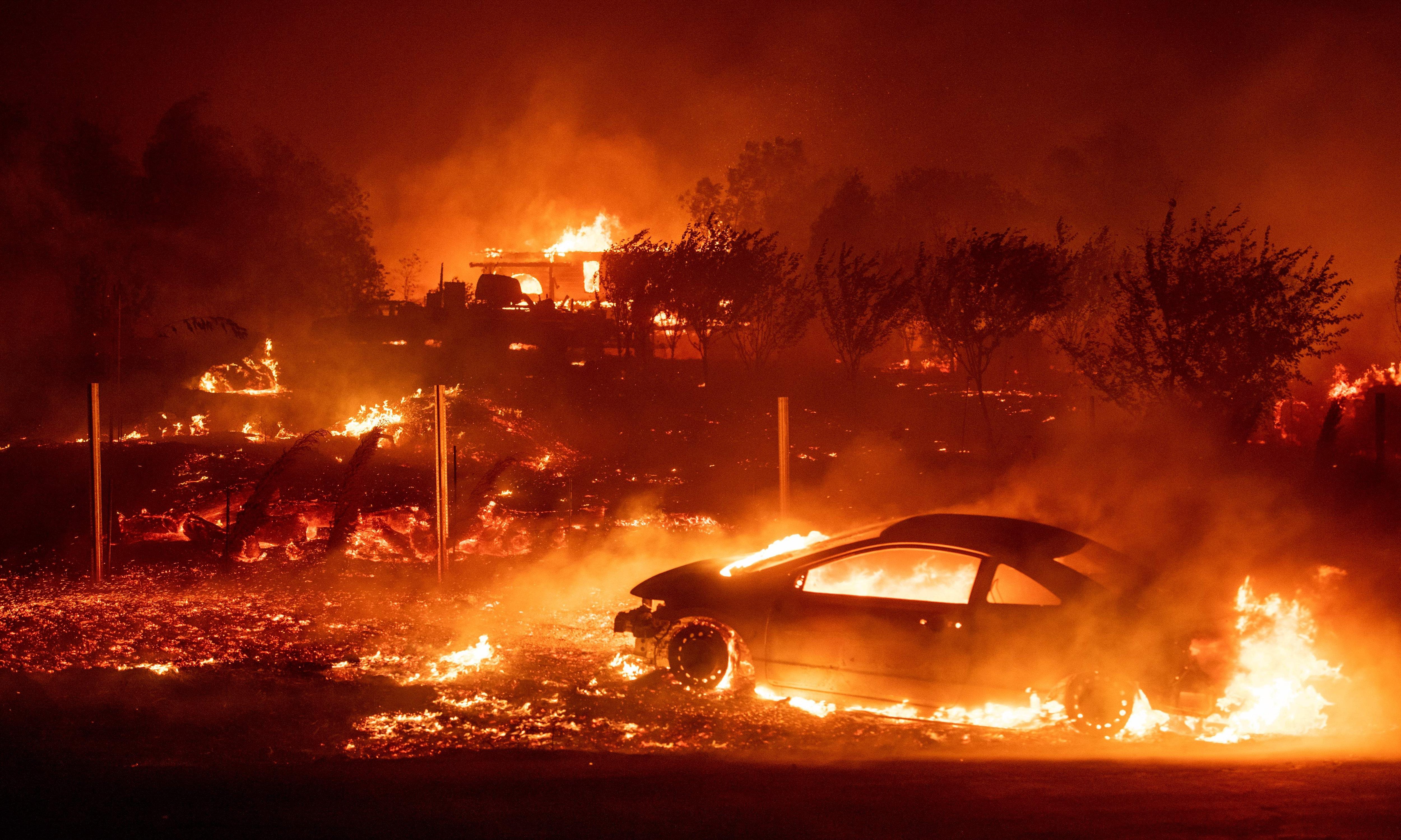 A car and a home burning in a wildfire